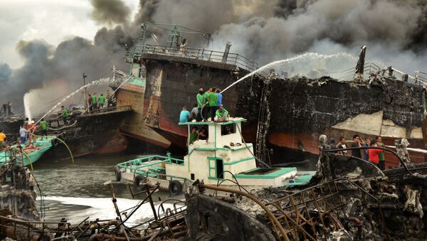 عمال إندونيسيون ورجال الإطفاء يخمدون حريق على قوارب الصيد في ميناء بينوا في دنباسار، في جزيرة بالي، إندونيسيا 9 يوليو/ تموز 2018 - سبوتنيك عربي