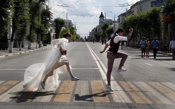متزوجان جدد يعبران الطريق، خلال إقامة بطولة كأس العالم روسيا-2018 في مدينة سامارا، روسيا 8 يوليو/ تموز 2018 - سبوتنيك عربي
