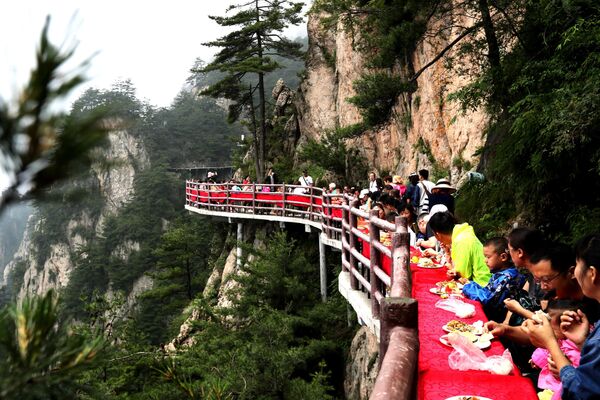 السياح خلال مأدبة طعام أقيمت على حافة جرف جبل لاوجون، على ارتفاع 2000 متر، في لويانغ بمقاطعة خنان بوسط الصين - سبوتنيك عربي