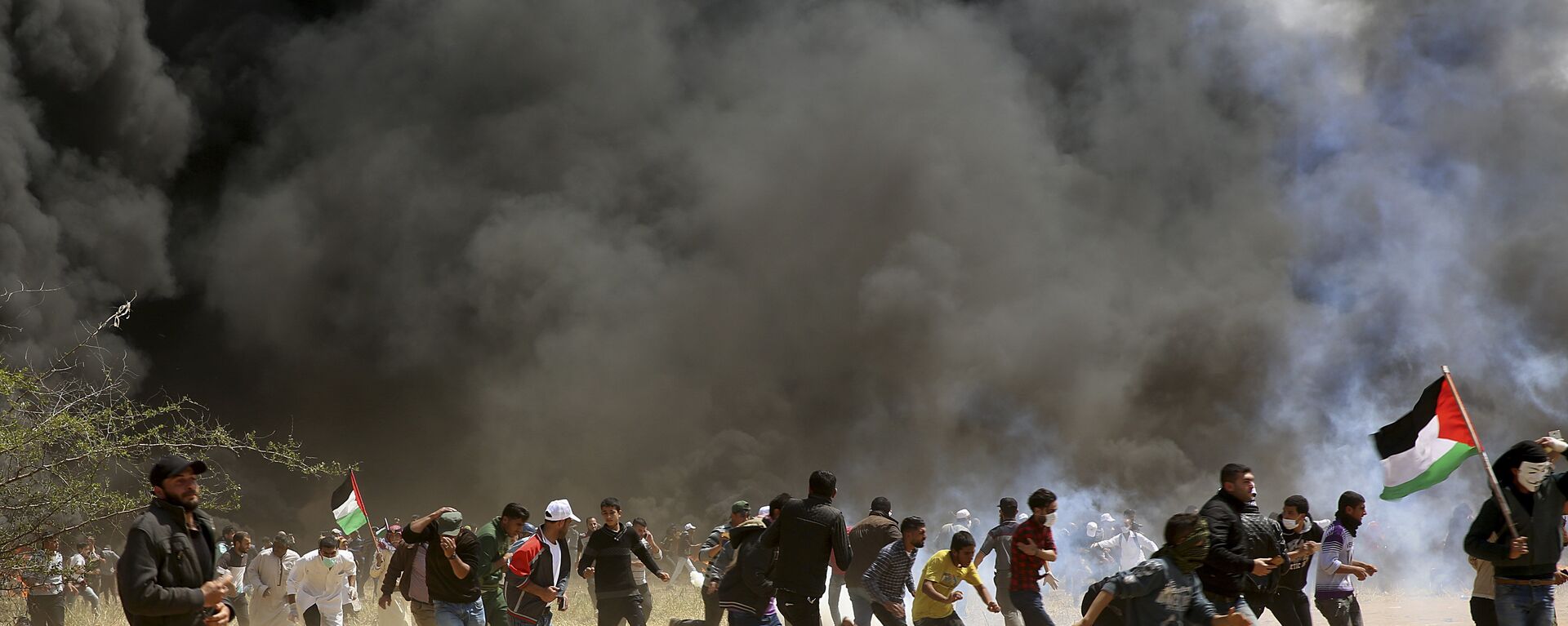 متظاهرون فلسطينيون يهربون من الغاز المسيل للدموع الذي أطلقه الجنود الإسرائيليون خلال اشتباكات مع القوات الإسرائيلية على طول حدود غزة مع إسرائيل ، شرق خان يونس ، قطاع غزة ، الجمعة 6 أبريل 2018 - سبوتنيك عربي, 1920, 08.05.2021