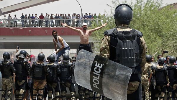 شرطة مكافحة الشغب العراقية تمنع المحتجين من اقتحام مبنى مجلس المحافظة خلال مظاهرة في البصرة، على بعد 550 كم جنوب شرق بغداد، العراق  15 يوليو/ تموز2018 - سبوتنيك عربي