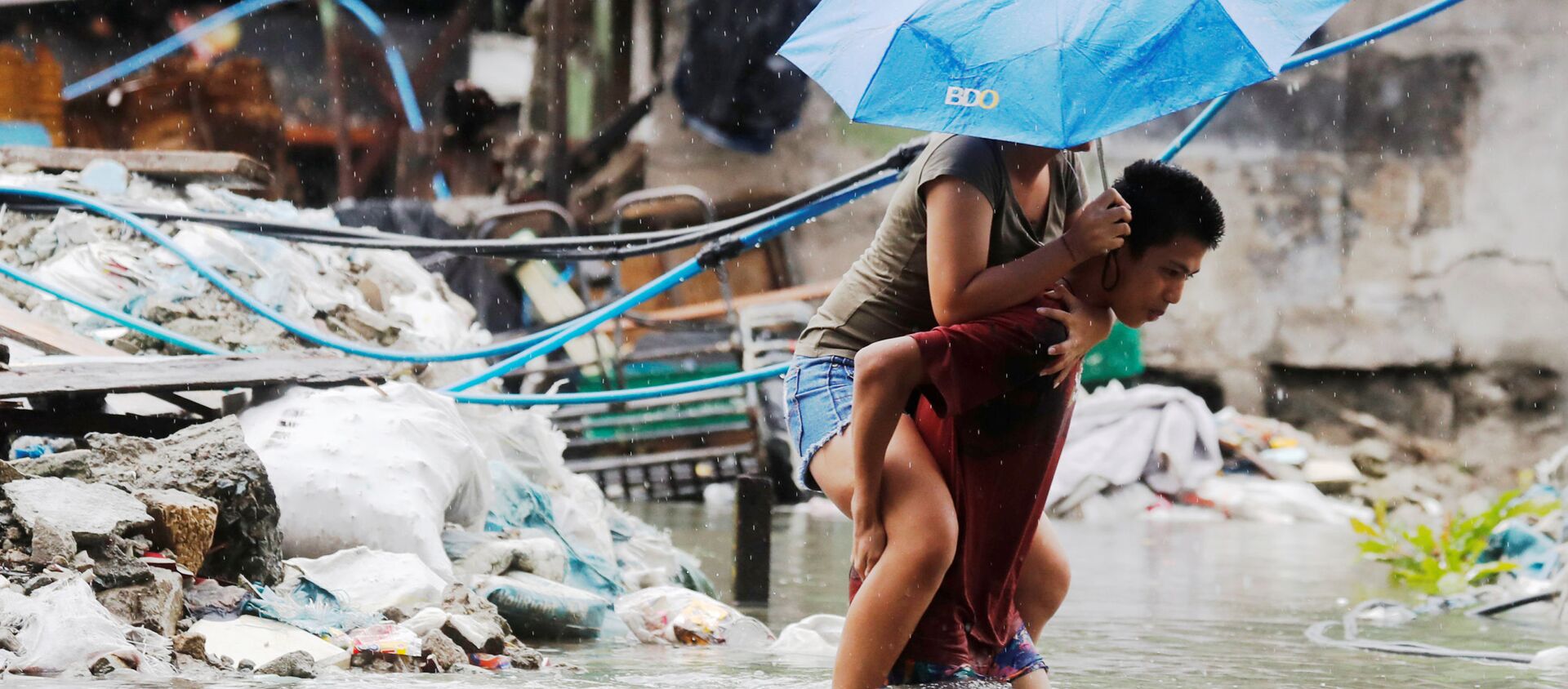 رجل يحمل امرأة على ظهره لعبور شارع مغمور بالمياه بعد  هطول أمطار موسمية وعاصفة مدارية سون-تينه في مدينة كويزون، مترو مانيلا، في الفلبين 17 يوليو/ تموز 2018 - سبوتنيك عربي, 1920, 24.07.2021