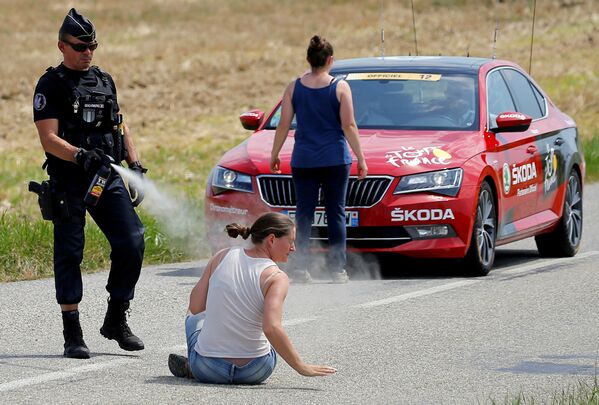 شرطي يرش غاز الفلفل في وجه امرأة محتجة خلال سباق فرنسا للدراجات، 24 يوليو/ تموز 2018 - سبوتنيك عربي