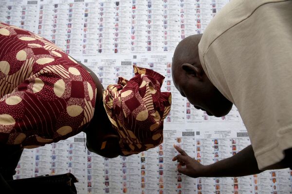 أشخاص يبحثون عن أسمائهم في القائمة الانتخابية في مركز الاقتراع في لافيابوغو، باماكو، مالي 23 يلويو/ تموز 2018 - سبوتنيك عربي