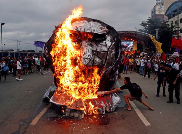 ناشطون يحرقون تمثالًا للرئيس الفلبيني رودريغو دوتيرتي لدى إلقائه خطابا حول حالة الأمة في مجلس النواب في مدينة كيزون-سيتي، مانيلا، الفلبين 23 يوليو/ تموز 2018 - سبوتنيك عربي