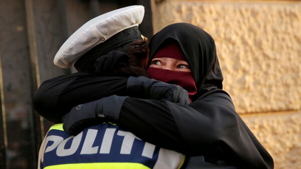 آية، 37 عاما، منقبة، تحتضن ضابط شرطة خلال مظاهرة ضد حظر الحجاب في كوبنهاغن، الدنمارك 1 أغسطس/ آب 2018 - سبوتنيك عربي