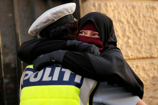 آية، 37 عاما، منقبة، تحتضن ضابط شرطة خلال مظاهرة ضد حظر الحجاب في كوبنهاغن، الدنمارك 1 أغسطس/ آب 2018 - سبوتنيك عربي