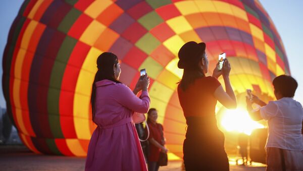 سياح يلتقطون صورا للمنطاد قبل انطلاقه  في رحلة في كابادوكيا، تركيا - سبوتنيك عربي