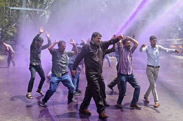 معلمون كشميريون يحتجون بشعارات مناهضة للحكومة بينما تفصلهم الشرطة الهندية بالمياه الملونة الأرجوانية خلال احتجاج في سريناجار في 9 أغسطس/ آب 2018 - سبوتنيك عربي