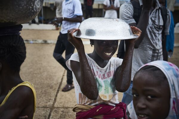 فتاة تقف مع وعاء معدني فوق رأسها في احتجاجات ضد الرئيس المالي الحالي في باماكو في 11 أغسطس/ آب2018 ، عشية الجولة الثانية من الانتخابات الرئاسية في مالي. - سبوتنيك عربي