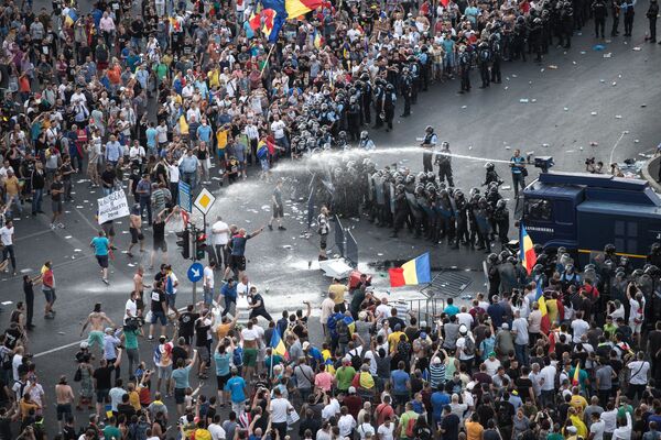 شرطة مكافحة الشغب تستخدم مدافع المياه ضد المتظاهرين أمام مقر الحكومة الرومانية في بوخارست، رومانيا في 10 أغسطس/ آب 2018 - سبوتنيك عربي