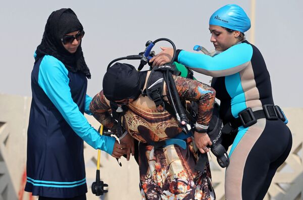 السعوديتان دانا القطري وبثينة اليوسف تساعدان زميلتهن مع أجهزة الغطس قبل بدء دروس الغطس، في شاطئ نصف القمر بمدينة الظهران، المملكة العربية السعودية، 15 سبتمبر/ أيلول 2018 - سبوتنيك عربي