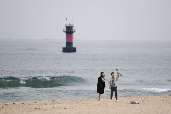شخصان يلتقطان صورة سيلفي على خلفية شاطئ مدينة غانغننغ، كوريا الجنوبية - سبوتنيك عربي