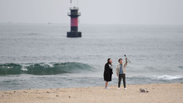 شخصان يلتقطان صورة سيلفي على خلفية شاطئ مدينة غانغننغ، كوريا الجنوبية - سبوتنيك عربي