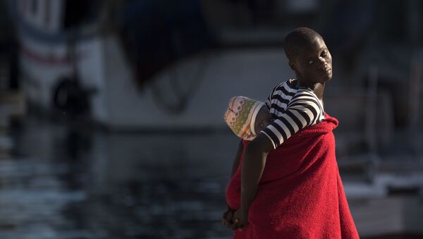لاجئة تحمل طفلها على ظهرها في ميناء مالقة، إسبانيا 23 سبتمبر/ أيلول 2018 - سبوتنيك عربي