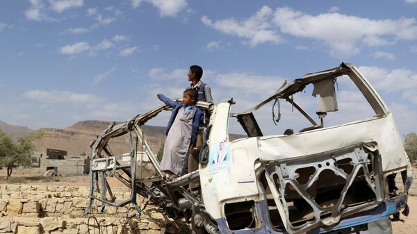 أطفال يقفون على حافلة تعرضت للدمار في صعدة - اليمن - سبوتنيك عربي