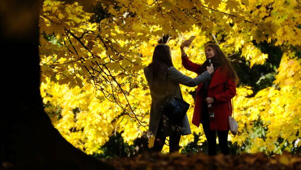فتاتان تلتقطان صور سيلفي على خلفية أشجار الخريف في منتزه كولومينسكويه الحكومي في موسكو - سبوتنيك عربي