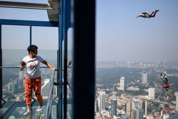 سائحة تنظر إلى القافزين من قاعدة القفز Kuala Lumpur Tower، من على ارتفاع 300 متر، في برج كوالا لمبور، ماليزيا في 30 سبتمبر/ أيلول 2018 - سبوتنيك عربي