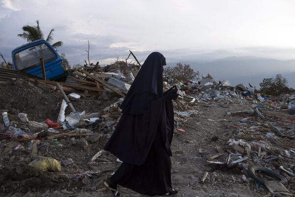 امرأة إندونيسية تسير بجوار منطقة لتجميع القمامة في قرية بيتبو، بالو 10 أكتوبر/ تشرين الأول 2018. يذكر أن هزة أرضية نتجت عنها تسوماني ضربت البلاد في 28 سبتمبر/ أيلول، مما أسفر عن مقتل ما يقارب 2000 شخص. - سبوتنيك عربي