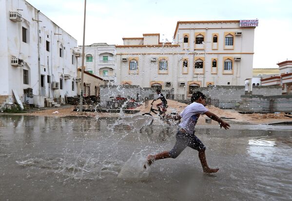 أطفال يلعبون بمياه الفياضانات بعد إعصار لبان في حي صلالة، عُمان 13 أكتوبر/ تشرين الأول 2018 - سبوتنيك عربي