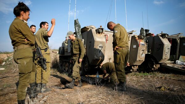 جنود إسرائيليون يقفون بالقرب من حاملات الجند المدرعة (APC) في حقل في جنوب إسرائيل ، بالقرب من الحدود مع غزة - سبوتنيك عربي