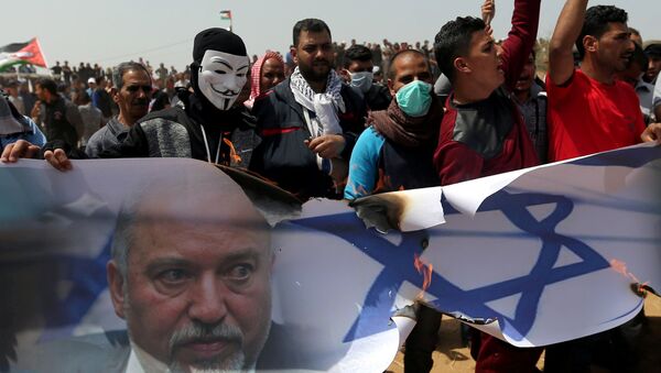 متظاهرون فلسطينيون يحرقون صورة لعلم إسرائيلي ووزير الدفاع الإسرائيلي أفيغدور ليبرمان خلال مظاهرة في جنوب قطاع غزة - سبوتنيك عربي