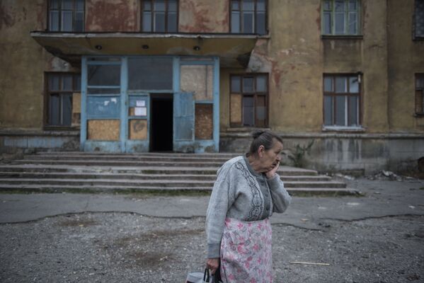 مواطنة تقف أمام مبنى سكني بمدينة ماكييفكا في منطقة دونيتسك، أوكرانيا - سبوتنيك عربي