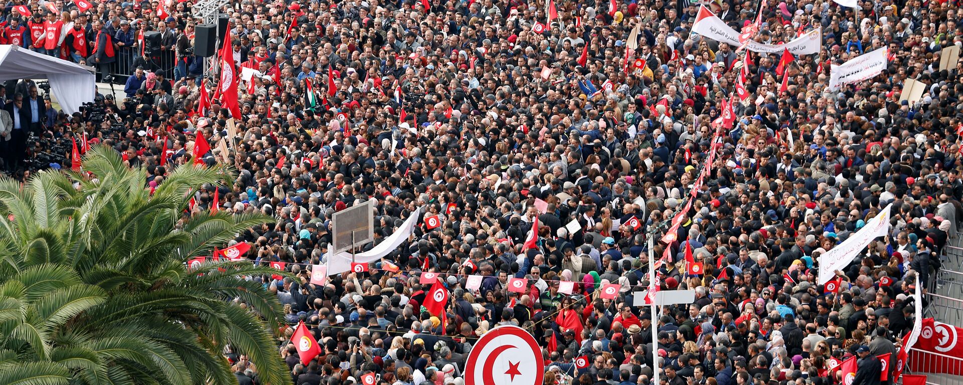 يحمل الناس أعلامًا وهم يحتجون على رفض الحكومة رفع الأجور في تونس العاصمة - سبوتنيك عربي, 1920, 21.12.2021