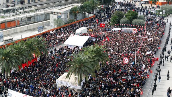 يحمل الناس أعلامًا وهم يحتجون على رفض الحكومة رفع الأجور في تونس العاصمة - سبوتنيك عربي