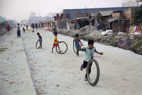 أطفال يلعبون بالعجل في مدينة دكا، بنغلادش - سبوتنيك عربي