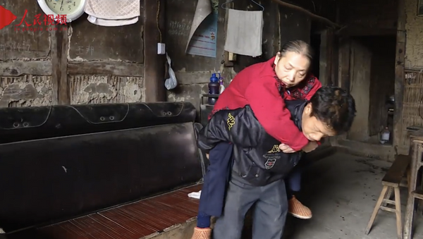 Стоп-кадр из видео о китайце, который в течении 15 лет носит свою парализованную мать на спине - سبوتنيك عربي