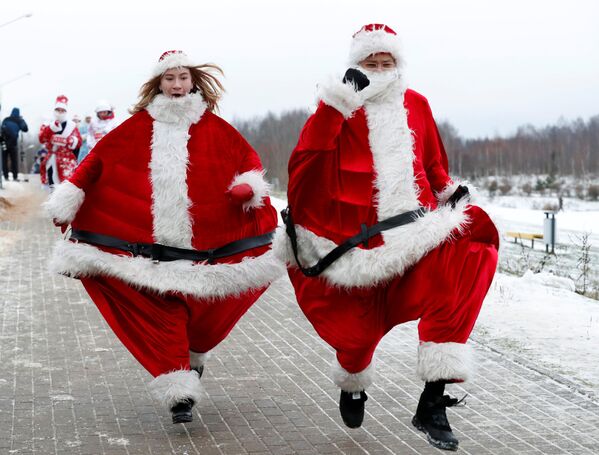 زوجان من بيلاروسيا يرتديان زي سانتا كلاوز (بابا نويل)، يشاركان في سباق سنوي حول بحيرة في مدينة مينسك، بيلاروسيا 15 ديسمبر/ كانون الأول 2018 - سبوتنيك عربي