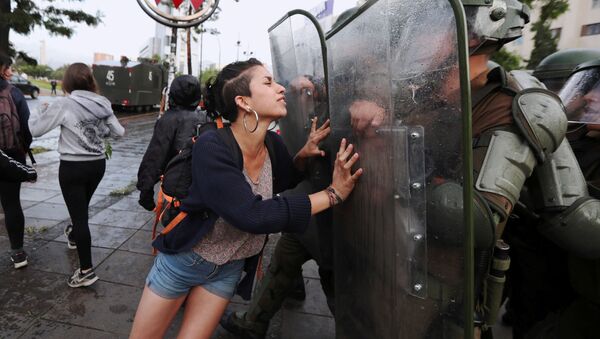 ناشطة من عشيرة مابوتشي تحاول وقف حركة عناصر الشرطة، أثناء مظاهرات في سانتياغو، تشيلي 14 ديسمبر/ كانون الأول 2018 - سبوتنيك عربي