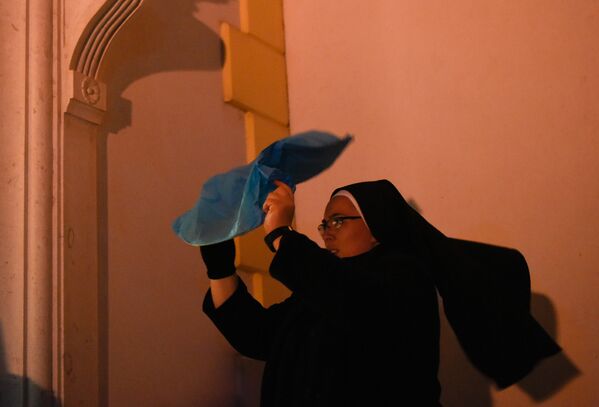 راهبة تحاول إشعال فانوس بعد احتفالات قداس عيد الميلاد في كنيسة غرب كوسوفو - سبوتنيك عربي