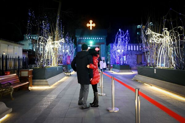 زوجان أمام الكنيسة الكاثوليكية قبل بدء قداس عيد الميلاد في بكين - سبوتنيك عربي