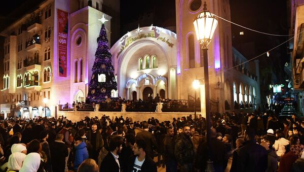 سكان مدينة اللاذقية السورية خلال الاحتفال بعيد الميلاد أمام كنيسة رئيسي الملائكة ميخائيل و جبرائيل - سبوتنيك عربي
