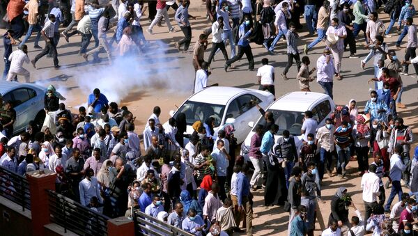 متظاهرون سودانيون يهربون من الغاز المسيل للدموع لتفريقهم أثناء مسيرتهم في الشارع خلال مظاهرات مناهضة للحكومة في الخرطوم - سبوتنيك عربي