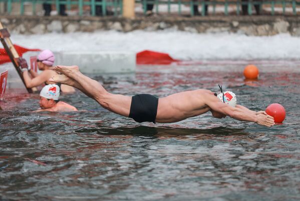 رجل خلال مسابقة للسباحة الشتوية عند درجة حرارة 21 درجة مئوية تحت الصفر بمقاطعة لياونينغ، شمال شرقي الصين - سبوتنيك عربي