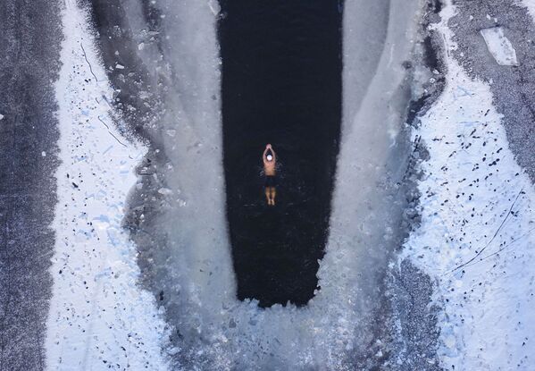 رجل يسبح في بحيرة متجمدة جزئيا في شنيانغ بمقاطعة لياونينغ - سبوتنيك عربي