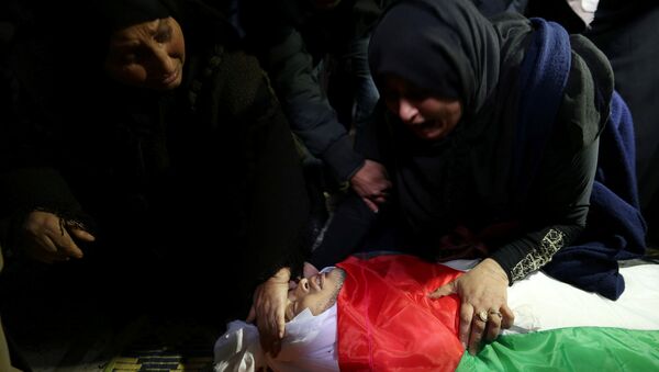 إحدى أقارب كرم فياض وهي تنظر إلى جثمانه خلال جنازته في جنوب قطاع غزة - سبوتنيك عربي