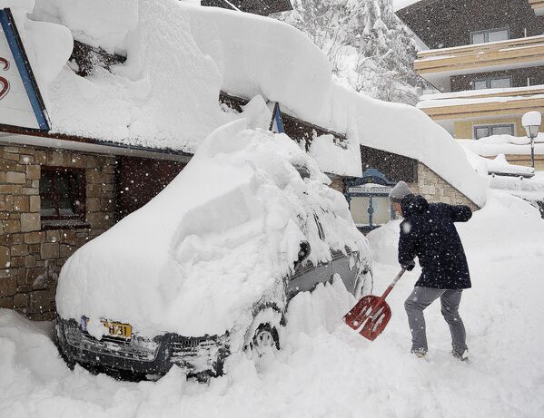 سائح يحاول تنظيف واخراج سيارته العالقة في الثلج في فيلزموس، النمسا 5 يناير/ كانون الثاني 2019 - سبوتنيك عربي