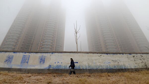 امرأة ترتدي قناعا وتسير وسط المباني في يوم ملوث في إحدى مقاطعات الصين - سبوتنيك عربي