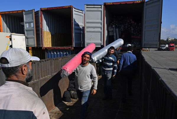 عمال يقومون بإفراغ حمولة حاويات في ميناء اللاذقية - سبوتنيك عربي