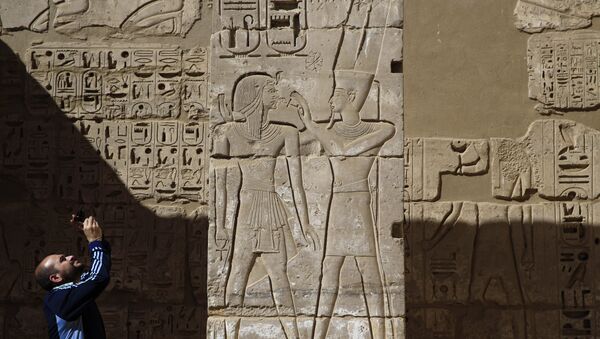 سائح يلتقط صورة لنقوش على معبد رمسيس الثالث في الأقصر - سبوتنيك عربي