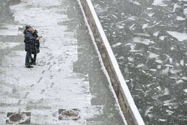 شخصان يلتقطان صورة سيلفي على خلفية تساقط ثلوج كثيف على ضفة نهر موسكو - سبوتنيك عربي