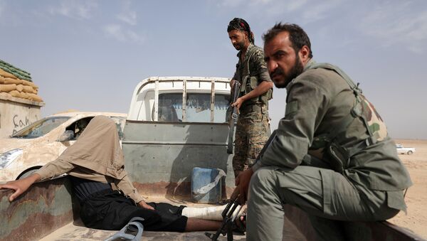مقاتلون من قوات سوريا الديمقراطية بعد القبض على جريح أثناء قتالهم مع داعش في المنطقة الشمالية من دير الزور في سوريا - سبوتنيك عربي