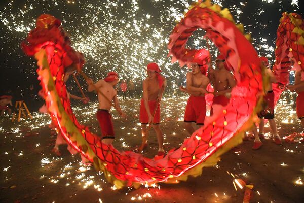 فنانون شعبيون خلال رقصة التنين، على خلفية شعلة لحديد منصهر خلال الاحتفالات بمهرجان المصابيح الصينية في آنشان بمقاطعة قويتشو، الصين 18 فبراير/ شباط 2019 - سبوتنيك عربي