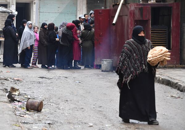 الحياة بعد الحرب، امرأة تحمل خبزا وتسير في أحد شوارع حي صلاح الدين في حلب، سوريا - سبوتنيك عربي
