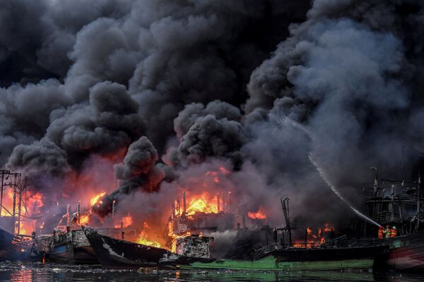 رجال الإطفاء يحاولون إطفاء قوارب الصيد التي اشتعلت فيها النيران في ميناء موارا بارو في جاكرتا، إندونيسيا ، 23 فبراير/ شباط 2019 - سبوتنيك عربي
