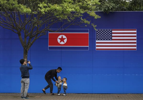 مواطنون يلتقطون صورة على خلفية علمي كوريا الشمالية والولايات المتحدة الأمريكية، في ظل القمة الأمريكية الكورية في هانوي، فيتنام 27 فبراير/ شباط 2019 - سبوتنيك عربي